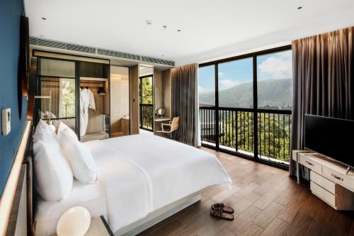 a bedroom with a large white bed and a large window at The Botanica Sanctuary in Puncak