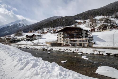 ein schneebedecktes Dorf mit einem Fluss und Gebäuden in der Unterkunft Zappartements in Kappl