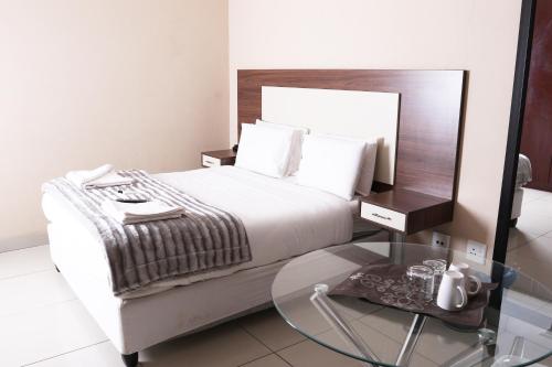 a bedroom with a bed and a glass table at Eagle Nest Luxury Accommodation in Roodepoort