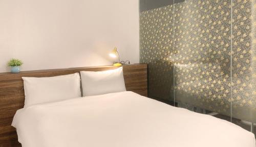 a bedroom with a white bed and a wall at 埔里城民宿 PuliTown BNB in Puli