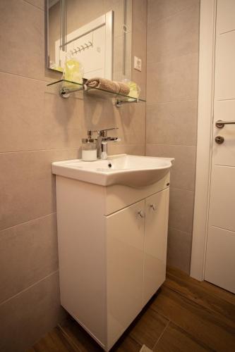 a bathroom with a white sink and a mirror at Jacuzzi Lux Apartman in Subotica