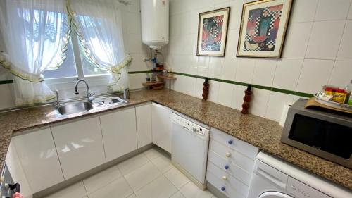 a kitchen with a sink and a microwave at Paraíso de playas y luz in Alcossebre