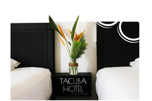 a vase of flowers on a table between two beds at Standard Queen Room two beds in Puerto Escondido