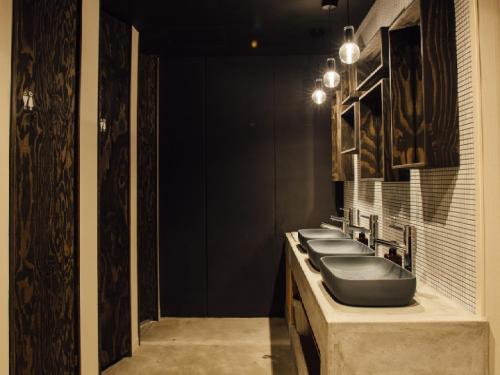 Baño con una fila de lavabos y paredes negras en Hostel Niniroom en Kioto