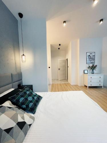 a bedroom with a large white bed and a dresser at BOOGIE Home Kamienica Łódzka in Łódź