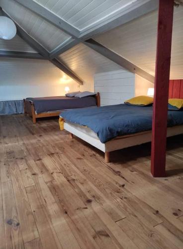 deux lits dans une chambre avec parquet dans l'établissement Maison Landaise chaleureuse, à Rion-des-Landes