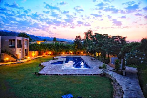 a backyard with a swimming pool and a house at The Golden Tusk By Ivory Destinations in Rāmnagar