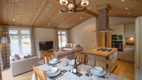 a kitchen and living room with a table and chairs at Llyn Conwy Lodge in Betws-y-coed