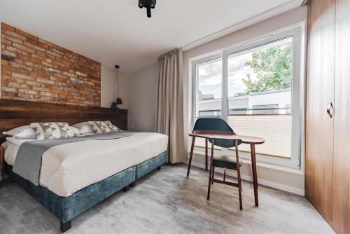 a bedroom with a bed and a desk and a window at Apartament Pionier41 in Szczecin