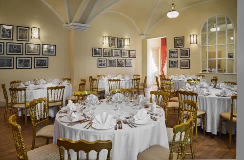 a room full of tables and chairs with white tablecloths at Palace Gate Hotel & Resort By EHM in Phnom Penh