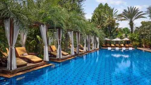 a pool at the resort with lounge chairs and palm trees at Palace Gate Hotel & Resort By EHM in Phnom Penh