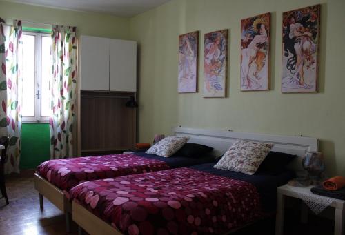 フィレンツェにあるAppartamento con terrazza in Santa Maria Novellaのベッドルーム1室(ベッド2台付)が備わります。壁には絵画が飾られています。