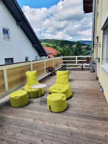 two yellow chairs and a table on a wooden deck at Forest Lodge in Bayerisch Eisenstein