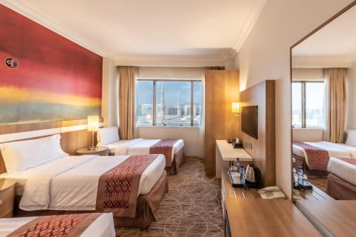 a hotel room with two beds and a television at Al Madina Golden Hotel in Medina