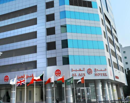 a building with a bunch of flags in front of it at Alain Hotel Ajman in Ajman 