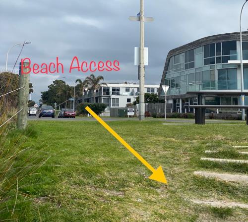 a yellow arrow on the grass in front of a building at Modern Beach Apartment with Pool & Location in Mount Maunganui