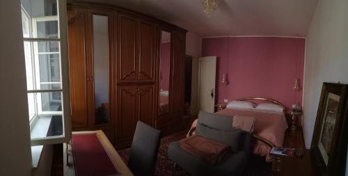 a bedroom with pink walls and a bed and a chair at Bike Civico 17 AFFITTA CAMERE in Venzone