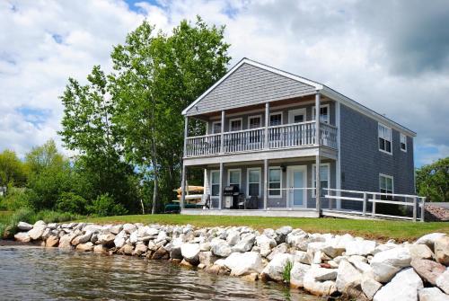 a house on the shore of a body of water at Keltic Quay Cottages & Bayfront Lodge in Whycocomagh