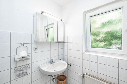 een witte badkamer met een wastafel en een raam bij Backskiste - Studioapartment im Erdgeschoss mit Gartenmitbenutzung in Flensburg