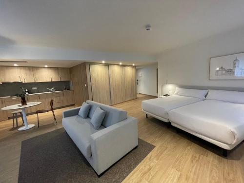 a bedroom with a large white bed and a couch at Apartamentos Forum Ceao in Lugo