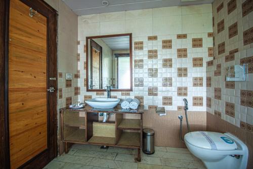 a bathroom with a sink and a toilet and a mirror at Snow Bloom Resort in Manāli