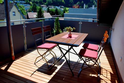 eine Holzterrasse mit einem Tisch und Stühlen auf dem Balkon in der Unterkunft Schottar FeWo MG 07 in Dornbirn