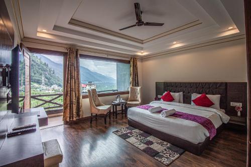 a bedroom with a large bed and a large window at Snow Bloom Resort in Manāli