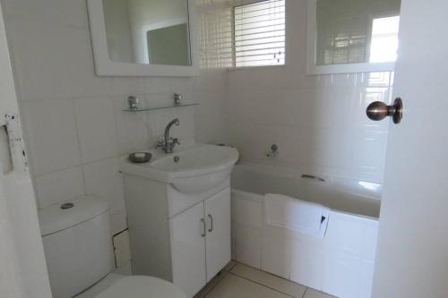 a white bathroom with a sink and a toilet at SEALODGE 23 UMHLANGA BEACHFRONT in Durban