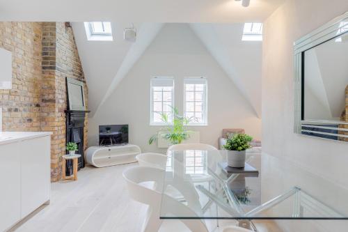 a white living room with a glass table and chairs at StayInn Holborn in London