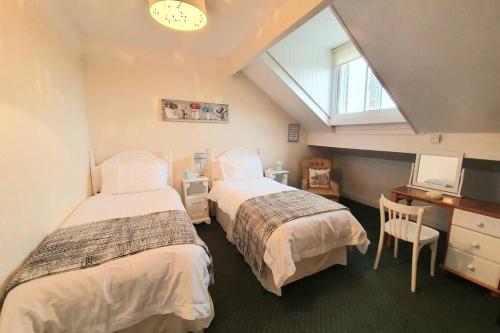 a bedroom with two beds and a desk and a window at Westfield House - Characterful 7 bedroom townhouse in Skipton