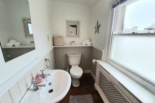 a bathroom with a toilet and a sink and a window at Westfield House - Characterful 7 bedroom townhouse in Skipton