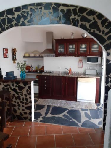 a kitchen with wooden cabinets and a stone wall at Casa do Montinho in Avis