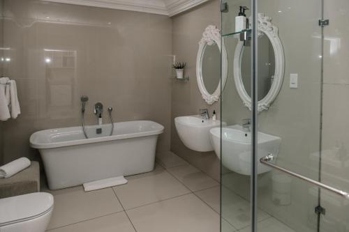 a bathroom with a tub and a toilet and a sink at The View Boutique Hotel & Spa in Amanzimtoti