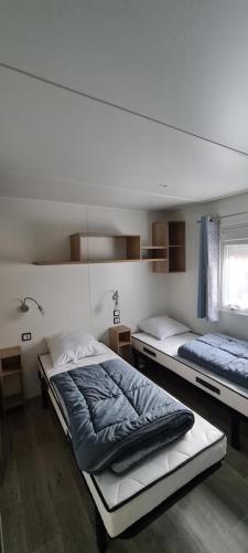1 Schlafzimmer mit 2 Betten und einem Fenster in der Unterkunft Mobilhome 2 ch,1 salon 40m2 de Charme dans camping *** in Saint-Julien-en-Born