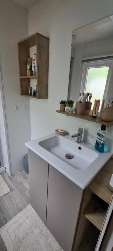 a white bathroom with a sink and a mirror at Mobilhome 2 ch,1 salon 40m2 de Charme dans camping *** in Saint-Julien-en-Born