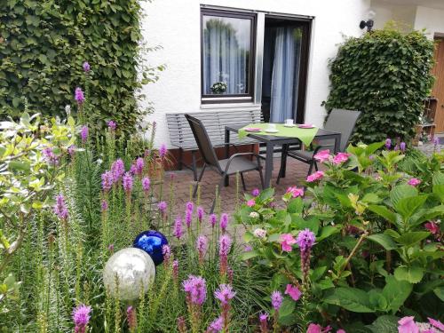 un jardín con mesa, sillas y flores en Annettes Ferienwohnung, en Michelstadt