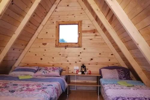 2 camas en una cabaña de madera con ventana en Kamp Bungalovi Sase drvena kuca en Višegrad