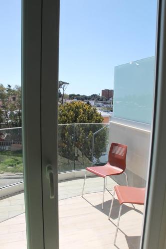 a balcony with a red chair and a view of the ocean at EKOTEL in Rome