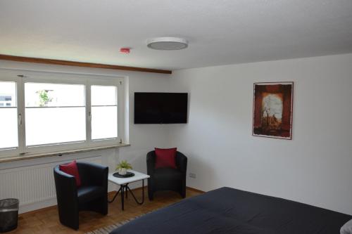 ein Schlafzimmer mit einem Bett und zwei Stühlen und einem Fernseher in der Unterkunft Schottar FeWo MG 07 in Dornbirn