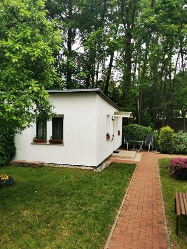 ein weißes Haus mit einem Backsteingang in einem Hof in der Unterkunft Ferienbungalow im Igelbau in Baabe