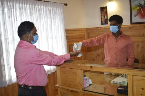 a man in a pink shirt and a man wearing masks at Altius Nest Hotel in Kodaikānāl
