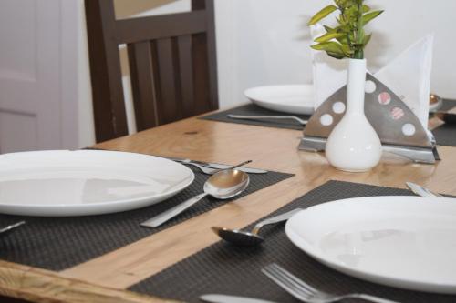 a wooden table with white plates and a vase on it at Altius Nest Hotel in Kodaikānāl