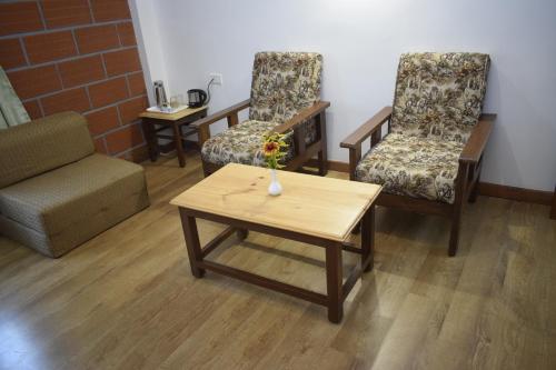 a room with two chairs and a table with a vase of flowers at Altius Nest Hotel in Kodaikānāl