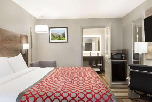a hotel room with a bed and a bathroom at Days Inn & Suites by Wyndham Bowling Green in Bowling Green
