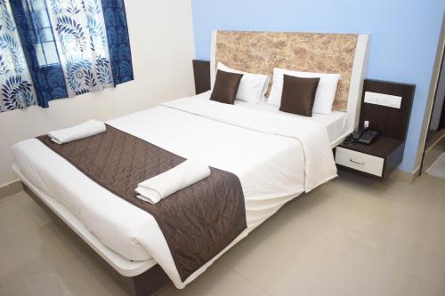 a bedroom with a large bed with white sheets and pillows at Bouvana Residency in Puducherry