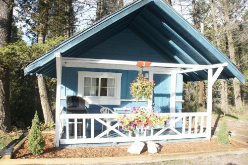 a blue shed with a white fence and flowers at Fairmont Mountain Bungalows in Fairmont Hot Springs