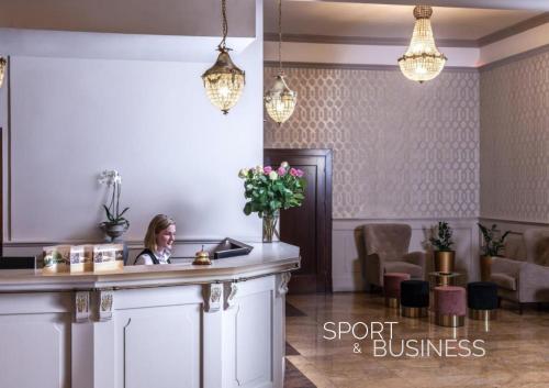 una mujer sentada en una recepción en el vestíbulo de un hotel en Hotel Cristal Park, en Dąbrowa Tarnowska