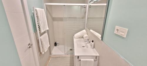 a white bathroom with a sink and a shower at Cozy White Home in Getxo in Getxo