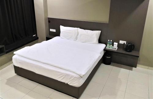 - un lit avec des draps et des oreillers blancs dans l'établissement Tropika Garden Hotel, à Johor Bahru