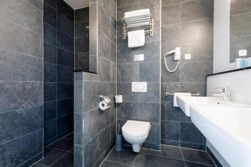 
a bathroom with a toilet, sink, and shower at Bastion Hotel Haarlem Velsen in Santpoort-Noord
